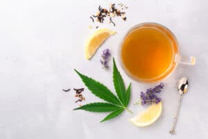 Marijuana leaf, lemon, lavender and cup of tea on marble slab