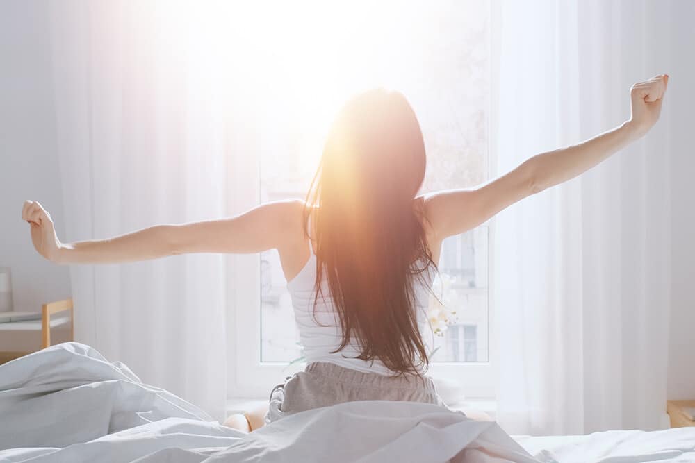 Woman stretching arms waking up from a good nights sleep