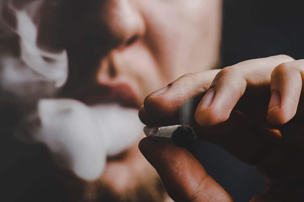 Close up of person smoking weed and blowing smoke