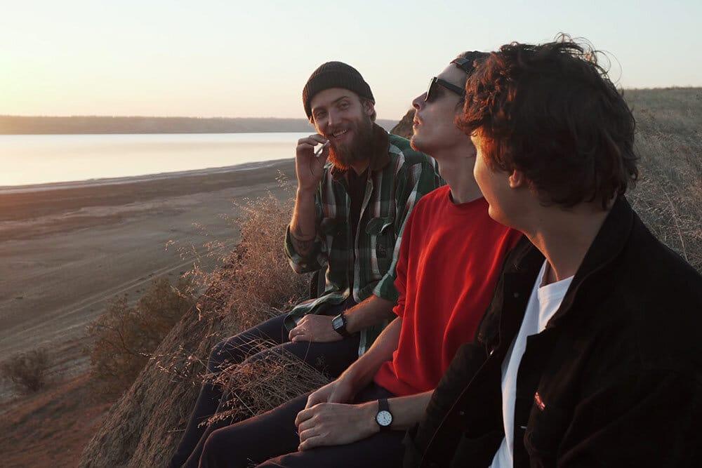 Group of friends sitting at the beach smoking marijuana