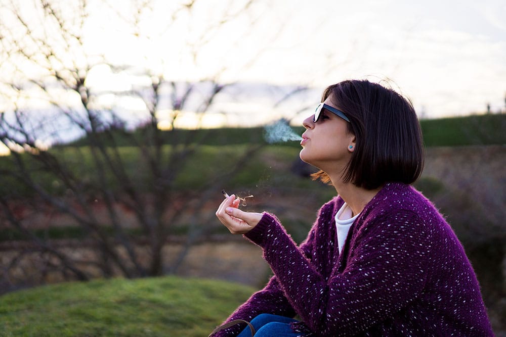 Woman relaxing and smoking weed outside