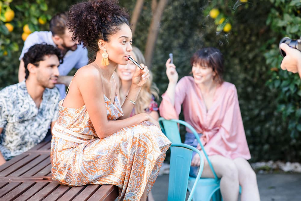 Happy woman vaping outside at pool party with friends in Santa Ana