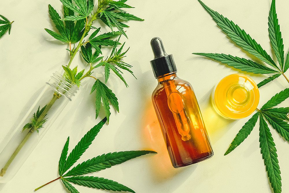 Cannabis tinctures and weed leaves spread out on table