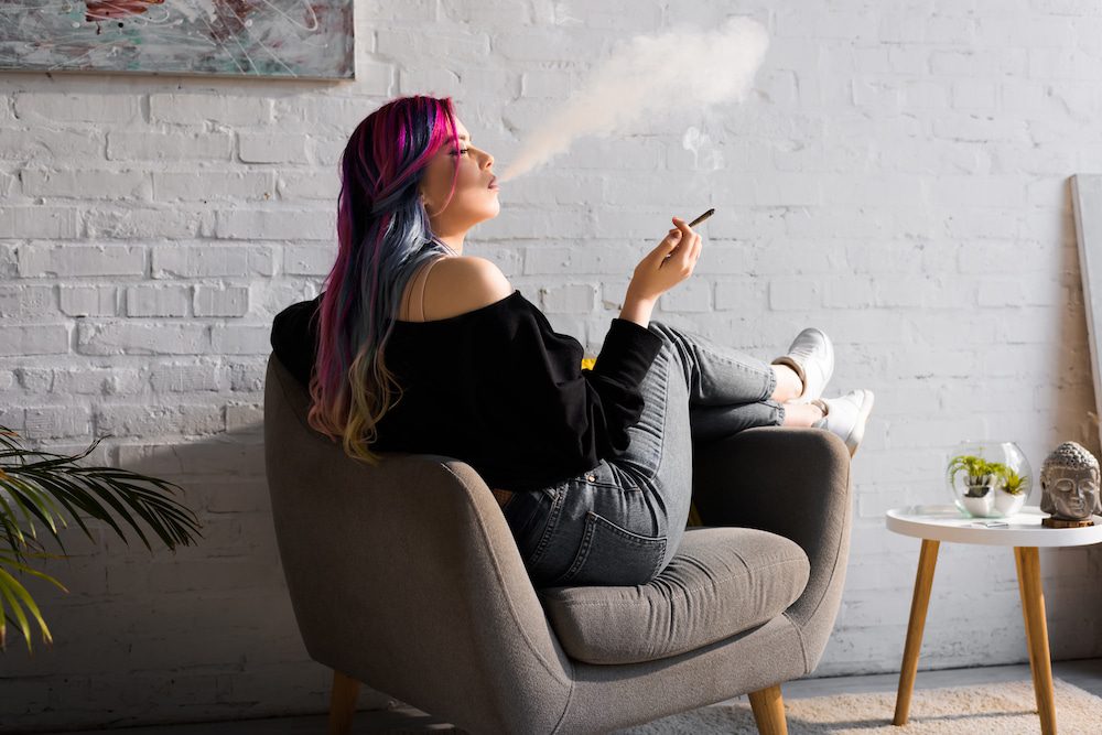 A woman smoking cannabis in a chair