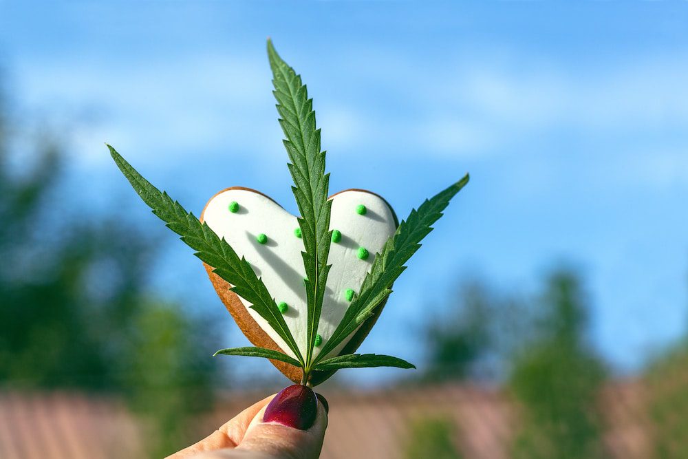 A heart-shaped cookie with a cannabis leaf