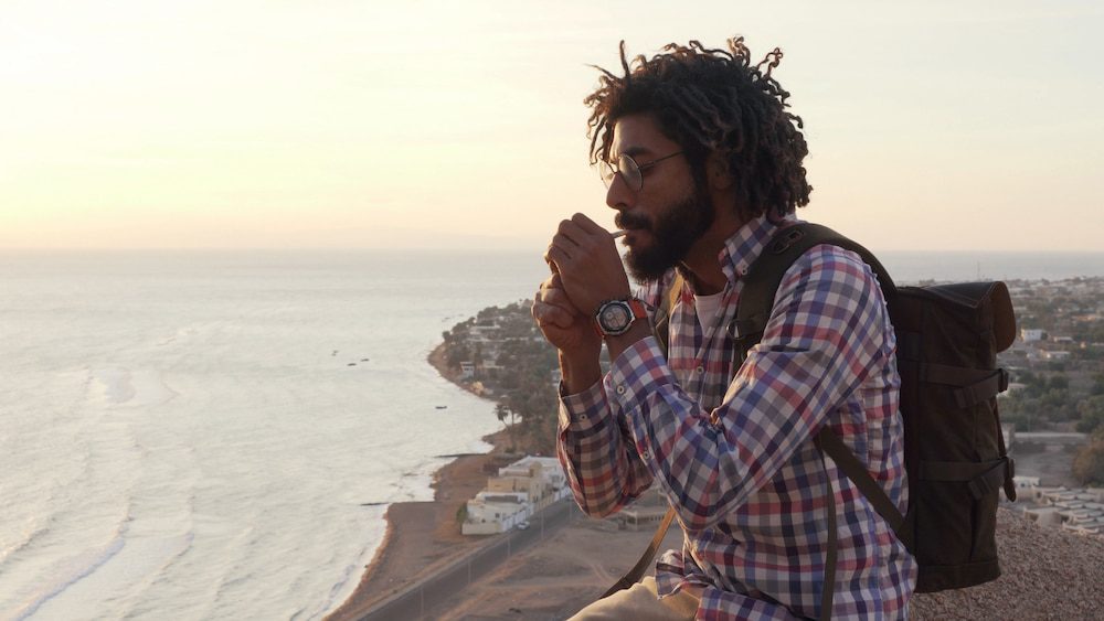 A young man smokes weed while out on a hike