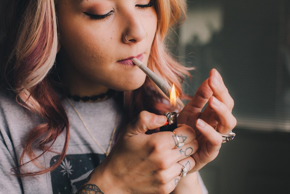 A young woman smokes a cannabis joint