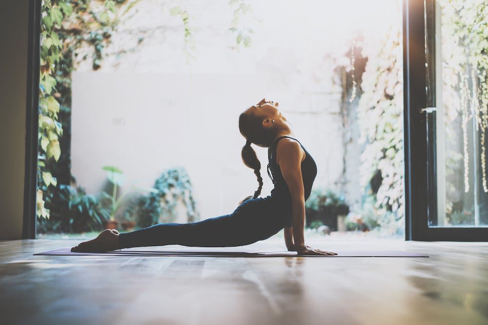 A young woman doing a yoga pose out on a patio