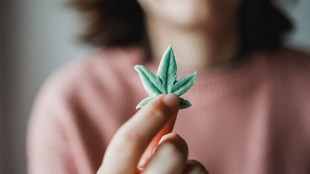 A woman holds up a piece of CBD candy