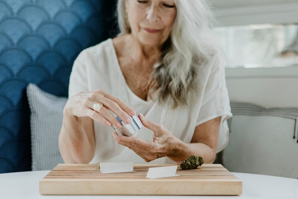 A senior woman rolls a joint for medical use