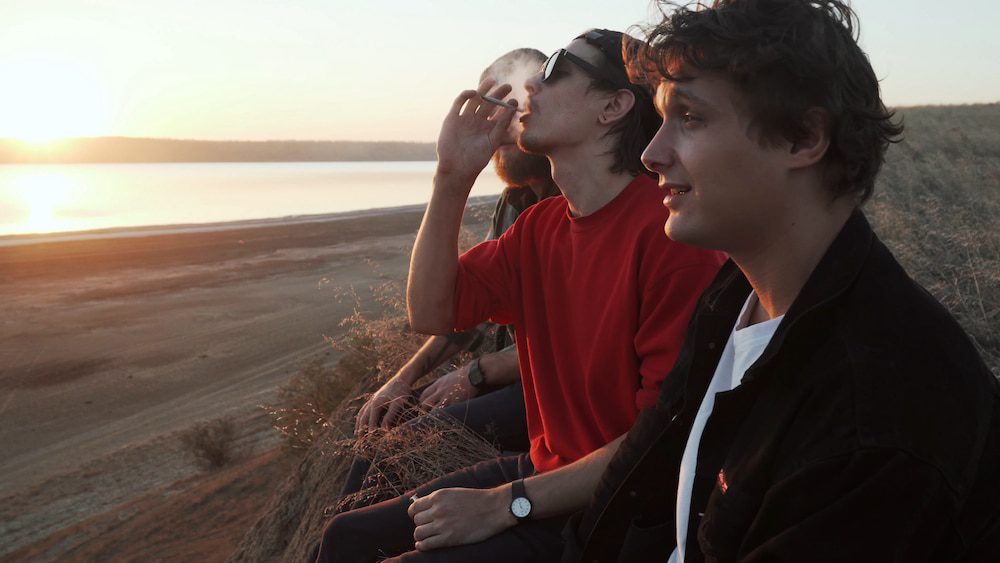 Three friends smoke cannabis by the beach