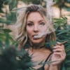 A woman smokes cannabis outdoors in a garden
