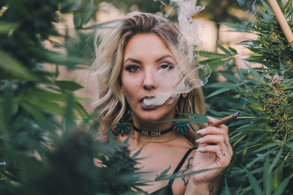 A woman smokes cannabis outdoors in a garden