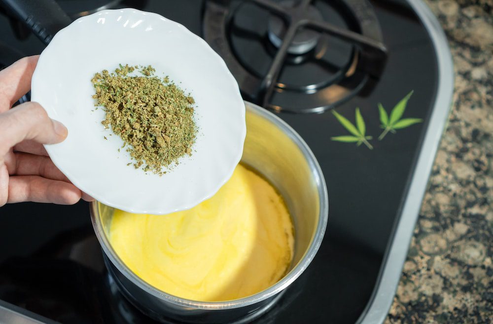 A man adding crushed cannabis to butter