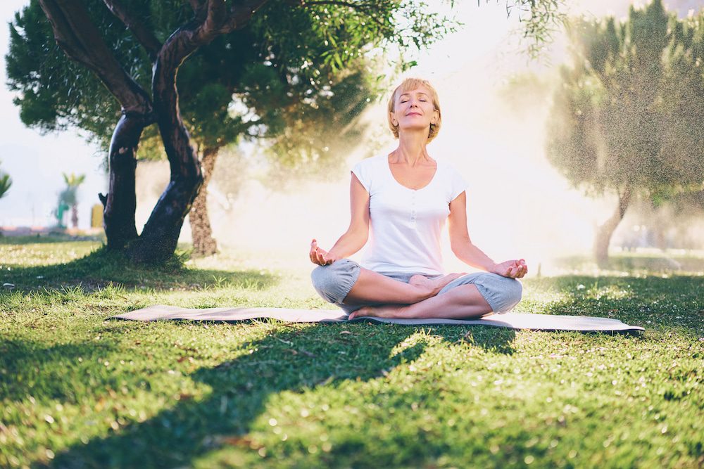 A senior woman practices yoga outdoors