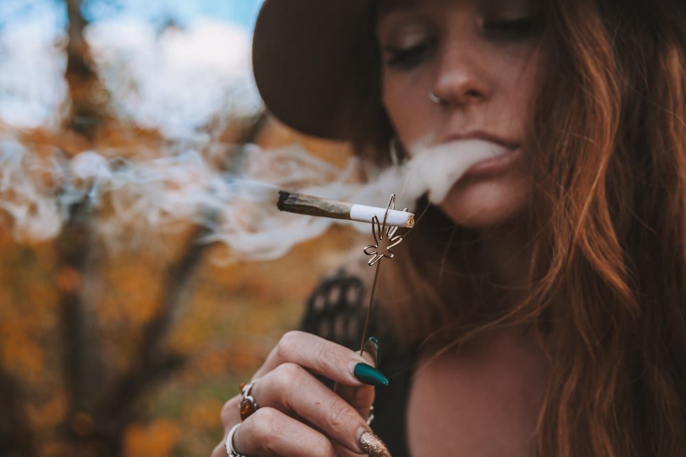 A woman smoking weed outside in the fall