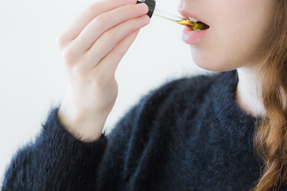 A woman using CBD oil as a sublingual