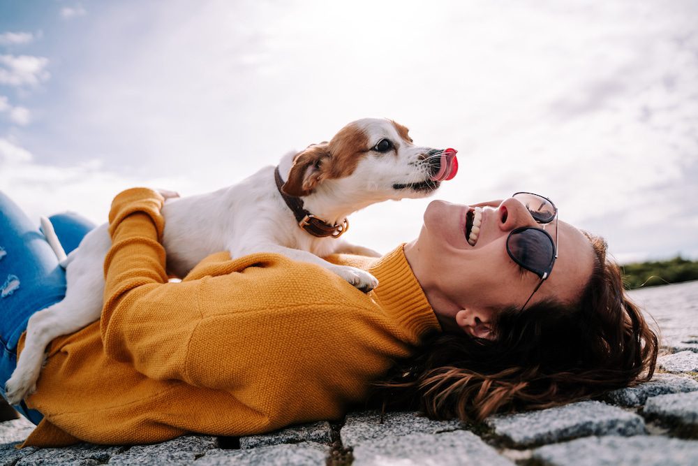 A happy woman playing outside with her dog